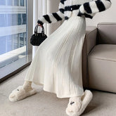 Person wearing a black and white striped sweater, white pants, and fluffy slippers in a living room.